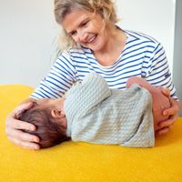 Portrait photo of Barbara Tamm, a friendly smiling osteopath wearing a blue and white striped shirt against a light background. Next to the image is the practice's welcome text.